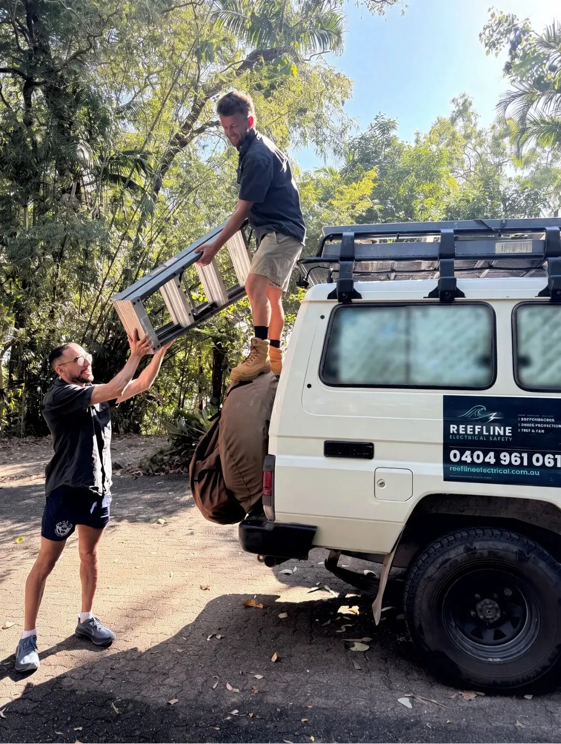 Ryan on the back of the Reefline ute, being passed a ladder by a teammate